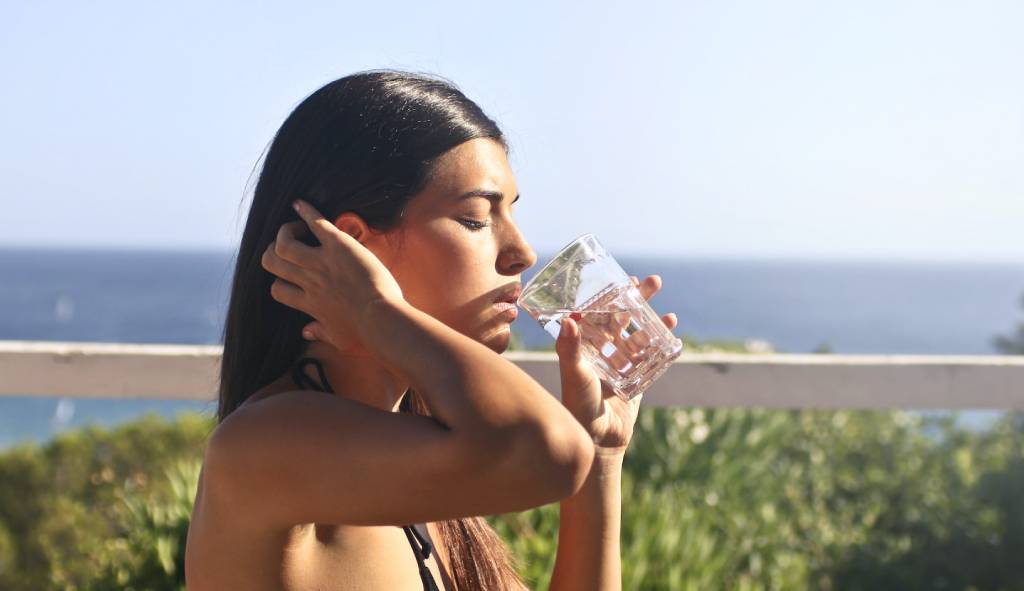 kobieta pijąca wodę - jak nawilżyć skórę twarzy
